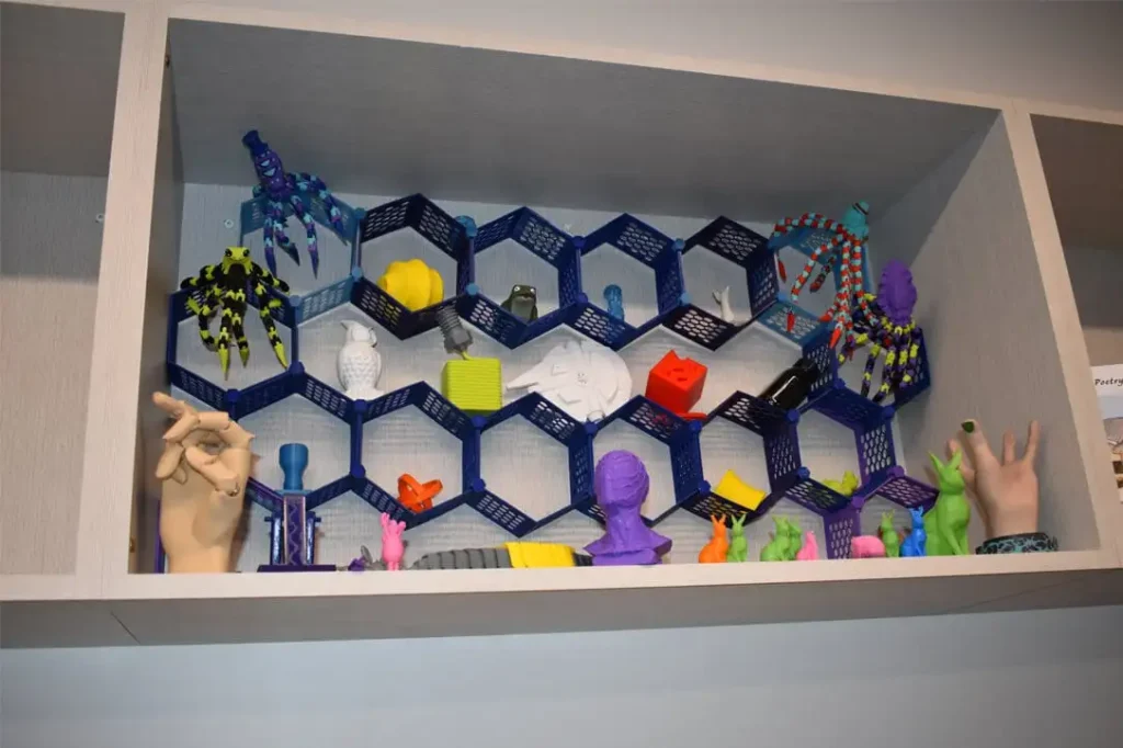 A creative display shelf featuring colorful community projects produced at a professional 3D printing library Texas makerspace lab