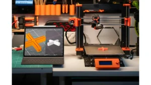 Industrial desktop 3D printer fabricating an engineering component next to a tablet running slicing software optimization